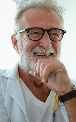 Older man with glasses smiling with his dental implants