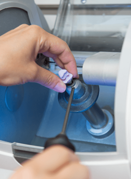 A woman using a milling machine to make a CEREC same-day dental crown