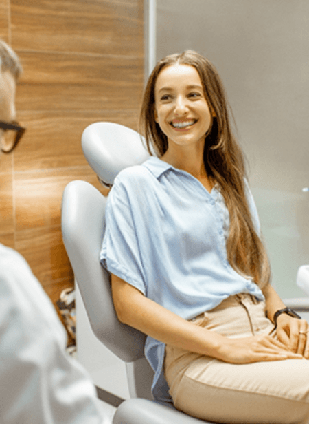 A smiling young woman talking with her dentist